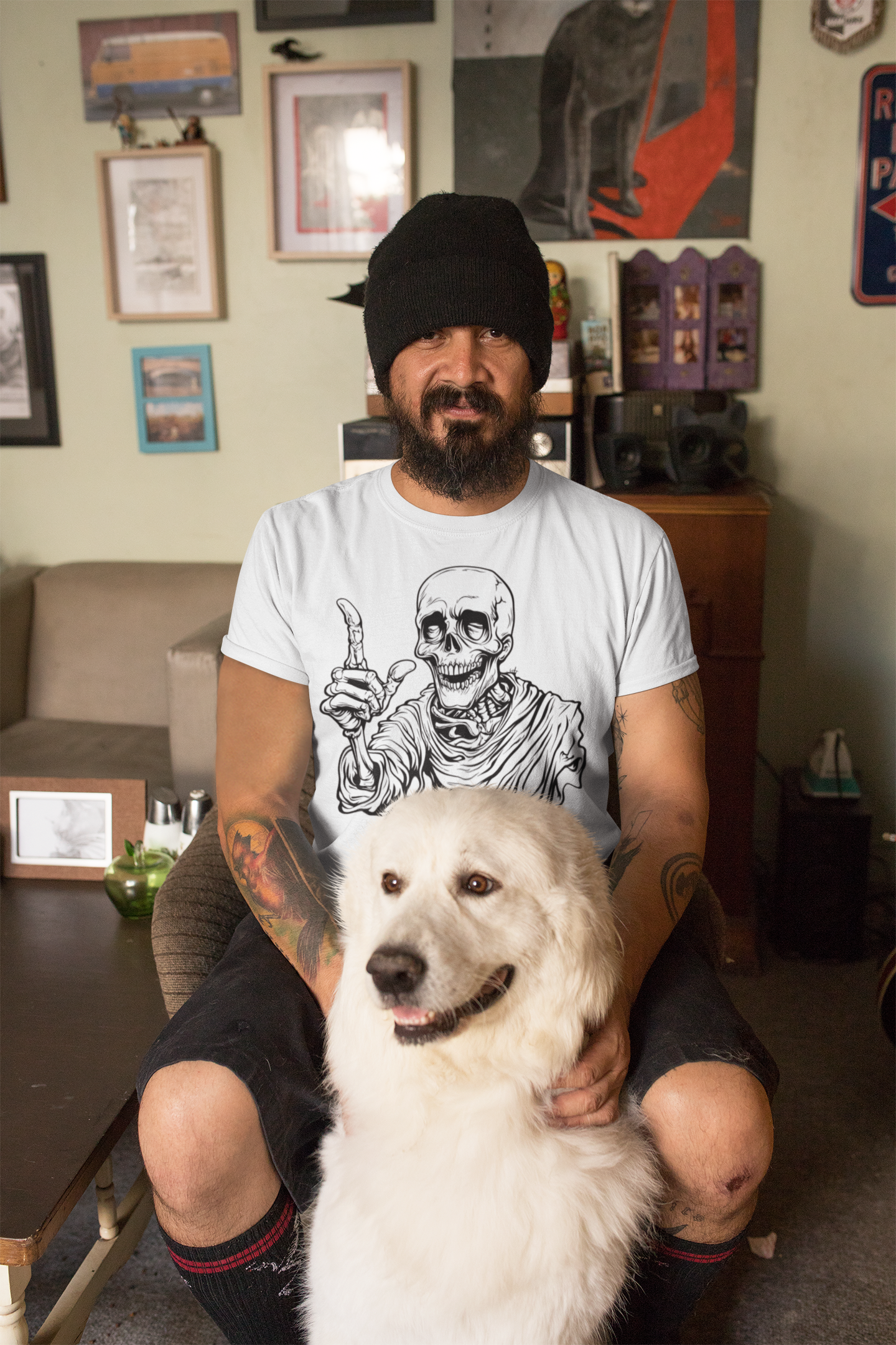 Man sitting with a white dog in a room with various posters on the wall.