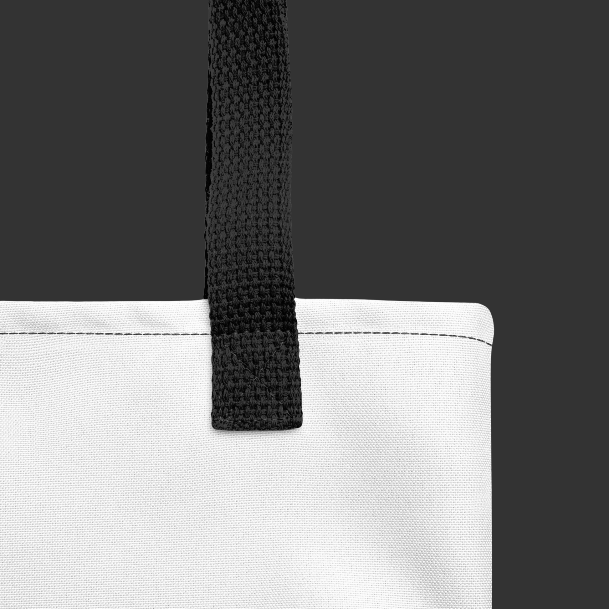 Close-up of a white tote bag with a black strap on a dark background